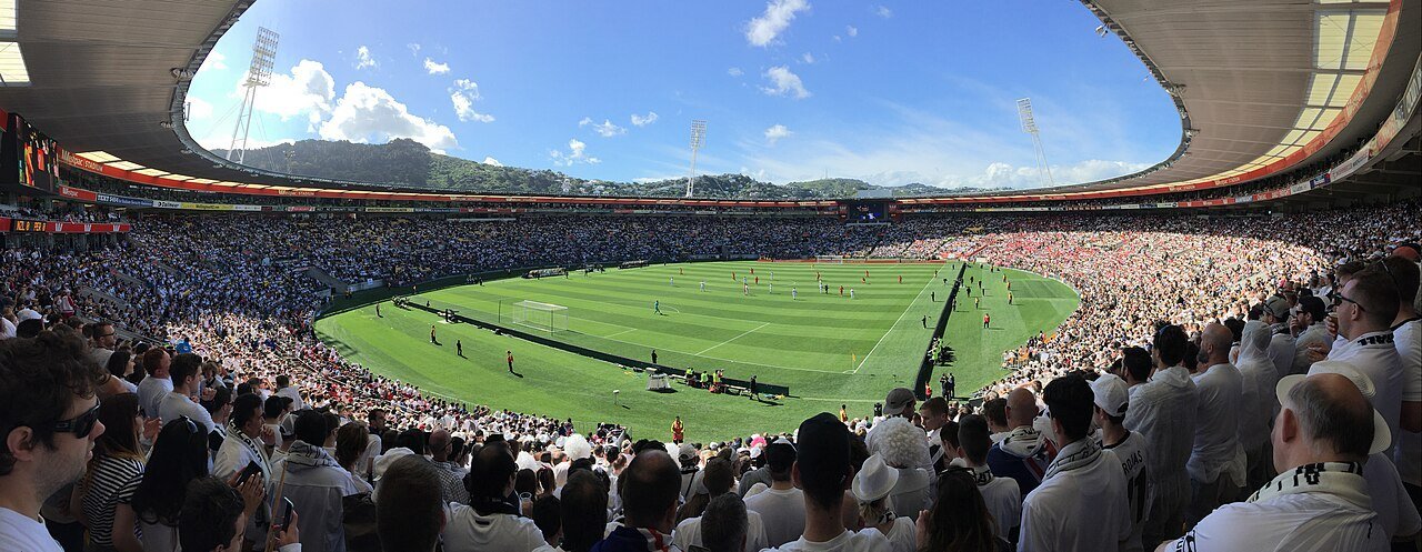 A wide view of a football match in a packed stadium